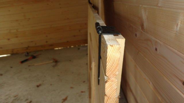 Installation des charnières dans le Z structurel de la porte d'un abri de jardin